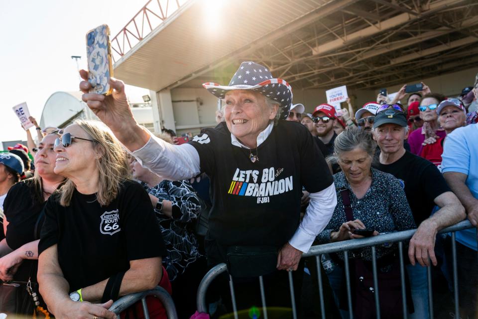 Cynthia Bartman of Claire County hangs over a rail to get video as former President Donald Trump speaks to a crowd of supporters during a rally at Avflight Saginaw in Freeland on Wed., May 1, 2024.