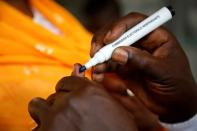 An election official puts ink on a voter's finger at a polling station during the legislative election in Abidjan