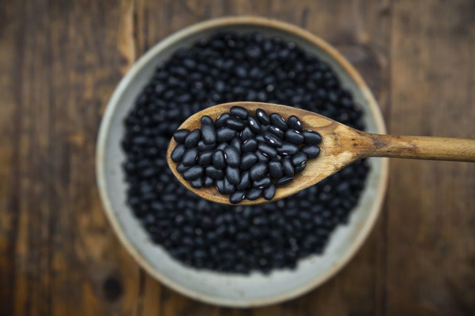 overhead view of spoon and bowl of black bean on wooden table