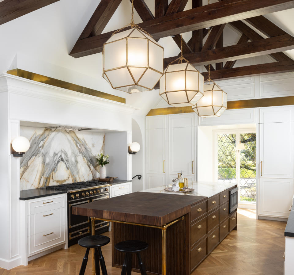 light kitchen cabinets and wood island; tall ceilings with large pendants