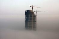 A building under construction is seen in fog in Rizhao, Shandong province, February 26, 2014. REUTERS/Stringer