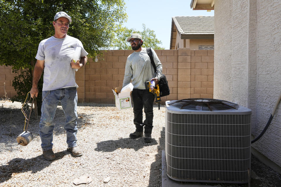 JP Lantin, left, owner of Total Refrigeration, and service tech Michael Villa, pick up their gear after replacing a fan motor on an air conditioning unit at a home as temperatures are expected to hit 117-degrees, Wednesday, July 19, 2023, in Laveen, Ariz. (AP Photo/Ross D. Franklin)