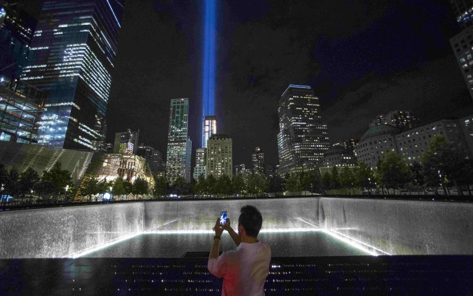 A man takes a photo at the 9/11 Memorial and Museum near the Tribute in Light in Lower Manhattan - Andrew Kelly