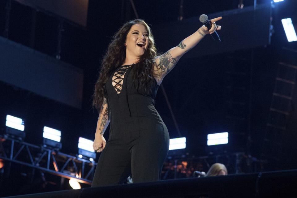 A woman in black holds a microphone and performs onstage