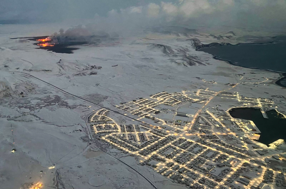 The evacuated town of Grindavik is seen as smoke billows and lava is thrown into the air. (AFP via Getty Images)