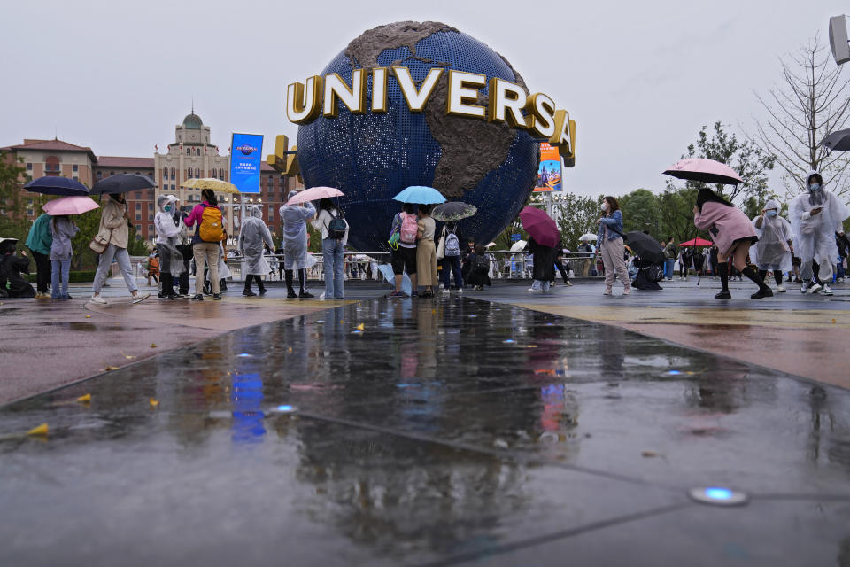 People gather and take selfies in a plaza near the entrance of the Universal Studios Beijing in Beijing, Monday, Sept. 20, 2021. Thousands of people brave the rain visit to the newest location of the global brand of theme parks which officially opens on Monday. (AP Photo/Andy Wong)