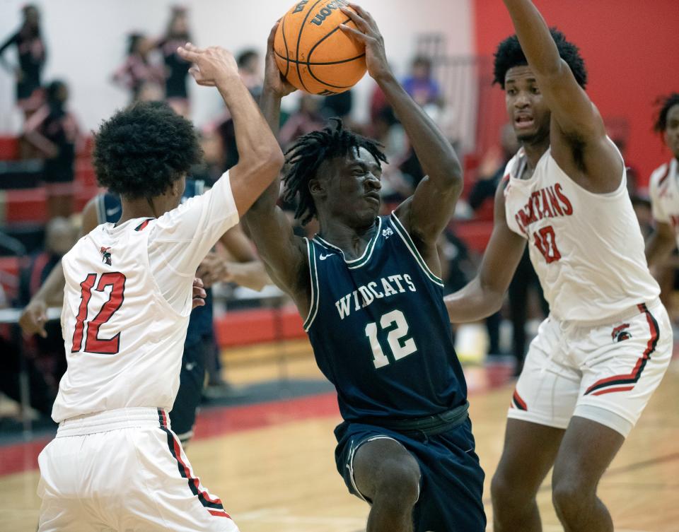 McKeel's Alex Sessoms (12) drives between Discovery's Malcom Smith (12) and Dontae Hines (10) on Thursday night in the semifinals of the Class 4A, District 7 tournament.