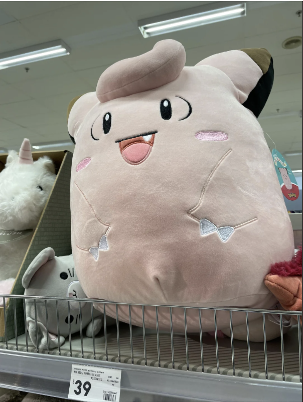 Large plush toy of Clefairy, a Pokémon, on a store shelf with other toys