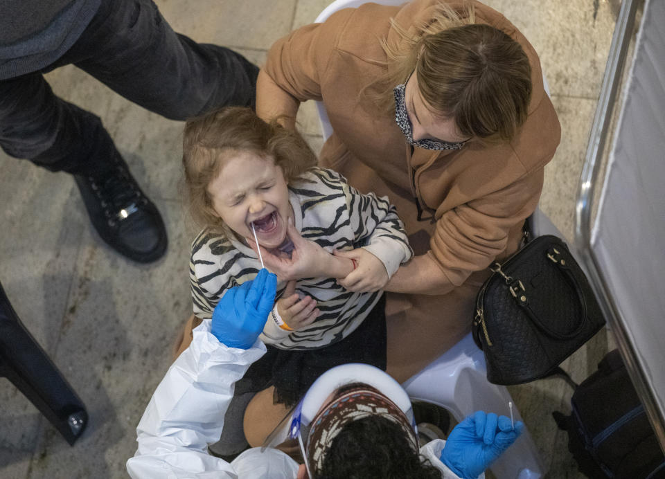 Medical personnel test a passenger for coronavirus as her mother holds her on their arrival in Israel, at Ben Gurion Airport near Tel Aviv, Israel, Sunday, Jan. 24, 2021, during a nationwide lockdown to curb the spread of the COVID-19 virus. (AP Photo/Ariel Schalit)