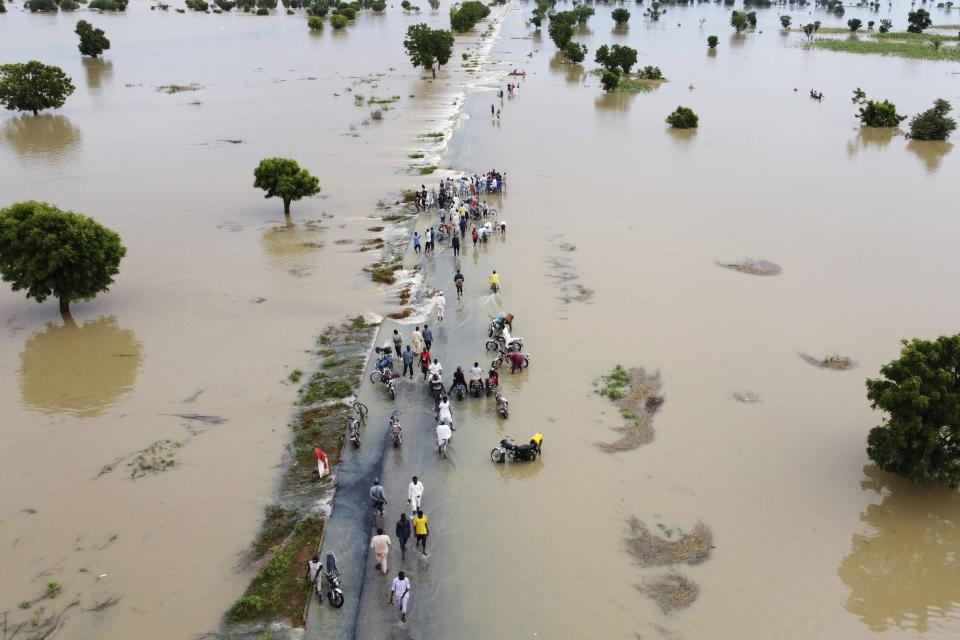 FILE - People walk through floodwaters after heavy rainfall in Hadeja, Nigeria, Sept 19, 2022. A major new United Nations report being released Monday, March 20, 2023, is expected to provide a sobering reminder that time is running out if humanity wants to avoid passing a dangerous global warming threshold. (AP Photo, File)