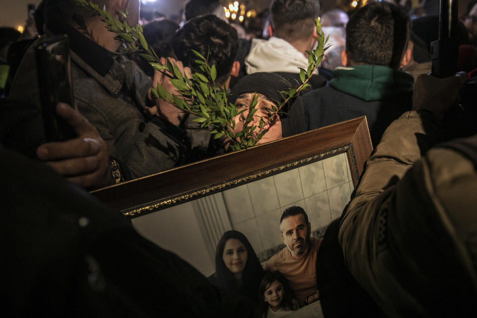 A woman holds a picture of her relatives, victims of the country's catastrophic earthquake during the one-year anniversary of the earthquake, in the city of Antakya, southern Turkey, Tuesday, Feb. 6, 2024. (AP Photo/Metin Yoksu)