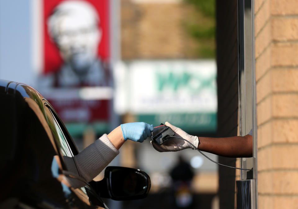 LONDON, UNITED KINGDOM - MAY 04: A worker takes a payment from a customer at KFC as it re-opens for Drive-Thru at a branch in Leyton on May 04, 2020 in London, United Kingdom. The country continued quarantine measures intended to curb the spread of Covid-19, but the infection rate is falling, and government officials are discussing the terms under which it would ease the lockdown. (Photo by Alex Pantling/Getty Images)