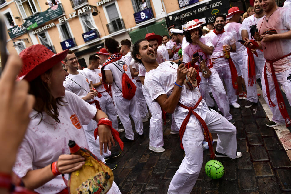 A reveler squirts wine from a wineskin while waiting for the launch of the 'Chupinazo' rocket, to mark the official opening of the 2022 San Fermin fiestas in Pamplona, Spain, Wednesday, July 6, 2022. The blast of a traditional firework opens Wednesday nine days of uninterrupted partying in Pamplona's famed running-of-the-bulls festival which was suspended for the past two years because of the coronavirus pandemic. (AP Photo/Alvaro Barrientos)