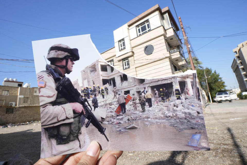 A photograph of a US soldier securing the area near a destroyed building after two car bombs detonated in a central Baghdad residential neighborhood, Friday, Nov. 18, 2005, killing at least six people and wounding dozens, is inserted into the scene at the same location Friday, March 10, 2023, 20 years after the U.S. led invasion on Iraq and subsequent war. (AP Photo/Hadi Mizban)