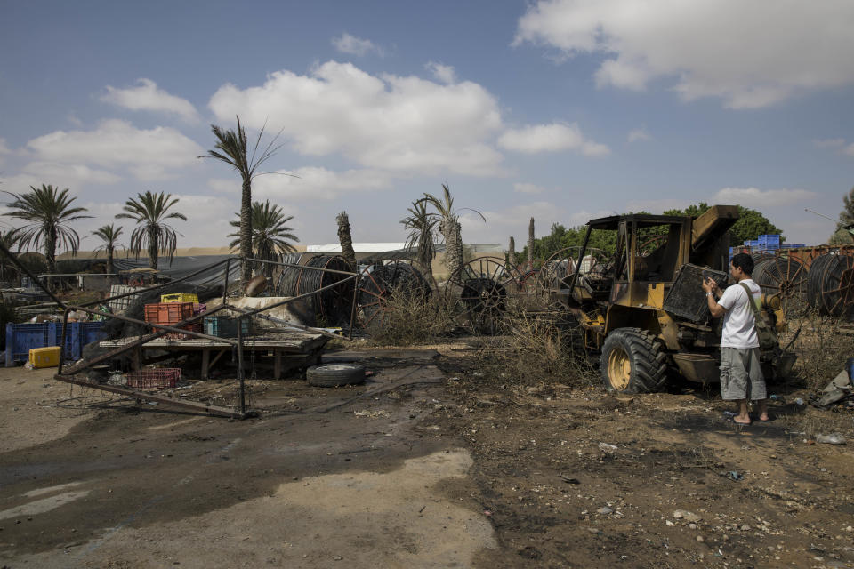 Thai worker photographs damage caused by a missile fired from gaza Strip at a farm near the Israel and Gaza border, Thursday, Aug. 9, 2018. Israeli warplanes struck dozens of targets in the Gaza Strip and three people were reported killed there, while Palestinian militants from the territory fired scores of rockets into Israel in a fierce burst of violence overnight and into Thursday morning. (AP Photo/Tsafrir Abayov)
