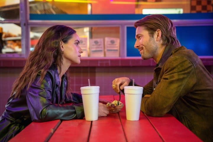 Two people talk at a table in Hit Man.