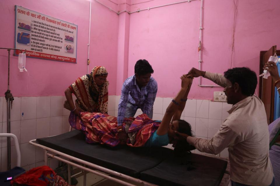 Nisha is lifted onto a hospital bed after undergoing sterilisation surgery on the same day as giving birth (Reuters)