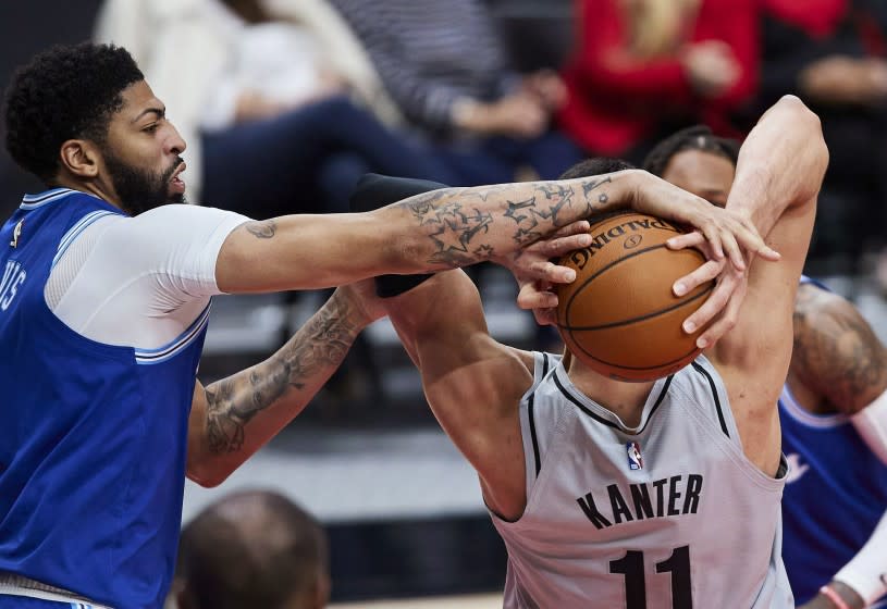 Los Angeles Lakers forward Anthony Davis, left, reaches for the ball held by Portland Trail Blazers center Enes Kanter during the second half of an NBA basketball game in Portland, Ore., Friday, May 7, 2021. (AP Photo/Craig Mitchelldyer)