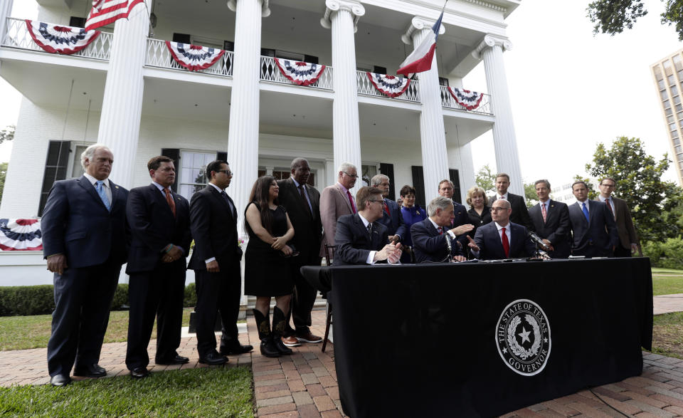 Seated at table from left, Lt. Governor Dan Patrick, Governor Greg Abbott, and Speaker of the House Dennis Bonnen, are joined with other law makers for a joint press conference to discuss teacher pay and school finance at the Texas Governor's Mansion in Austin, Texas, Thursday, May 23, 2019, in Austin. (AP Photo/Eric Gay)