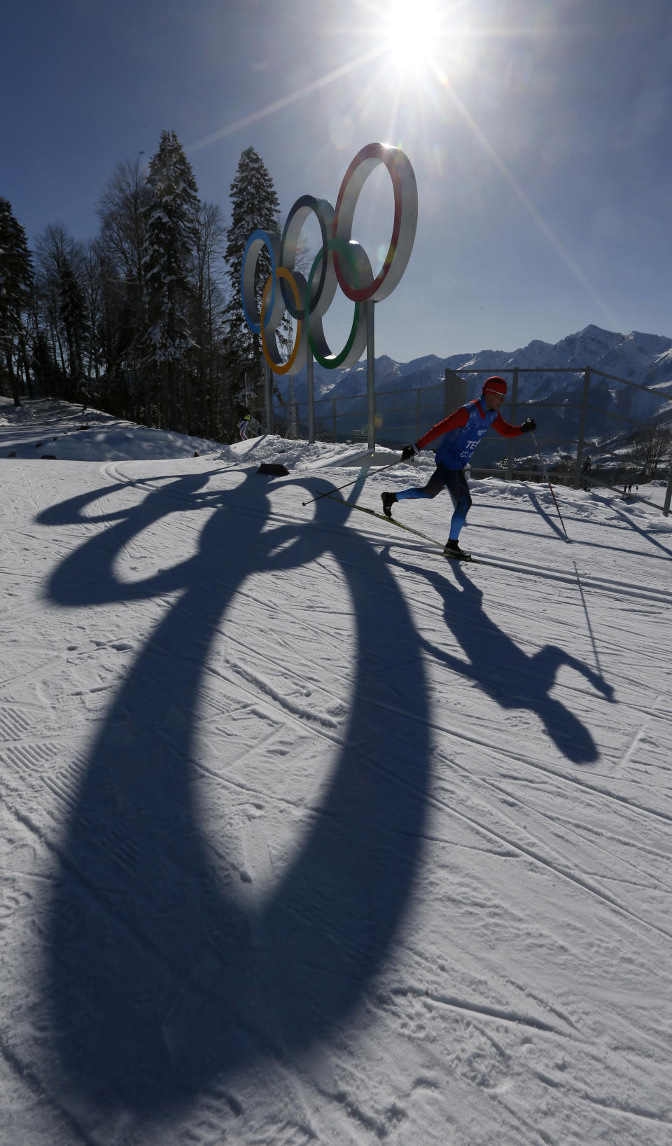 An unidentified Cross Country skier passes by the Olympic rings in the Cross Country stadium of the 2014 Winter Olympics, Tuesday, Feb. 4, 2014, in Krasnaya Polyana, Russia. (AP Photo/Dmitry Lovetsky)
