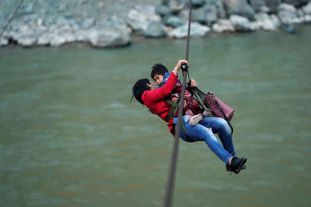 Cha Huilan, a 40-year old Lisu woman, and her daughter leave Lazimi village with a zipline across the Nu River in Nujiang Lisu Autonomous Prefecture in Yunnan province, China, March 24, 2018. Picture taken March 24, 2018. REUTERS/Aly Song