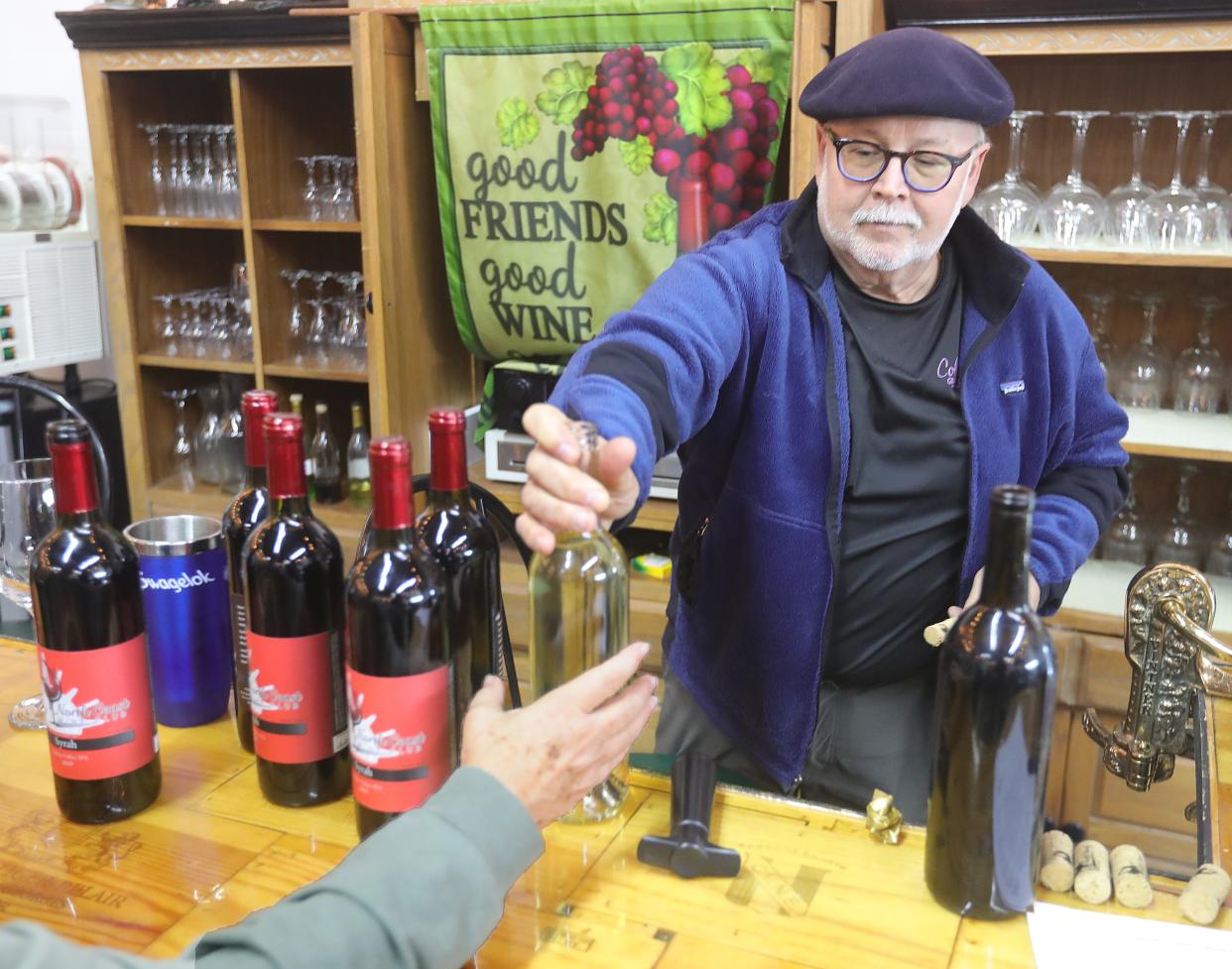 Tom Radu, founder of the North Coast Wine Club, passes out a bottle of "working wine" during the group's bottling event April 16 in Solon.