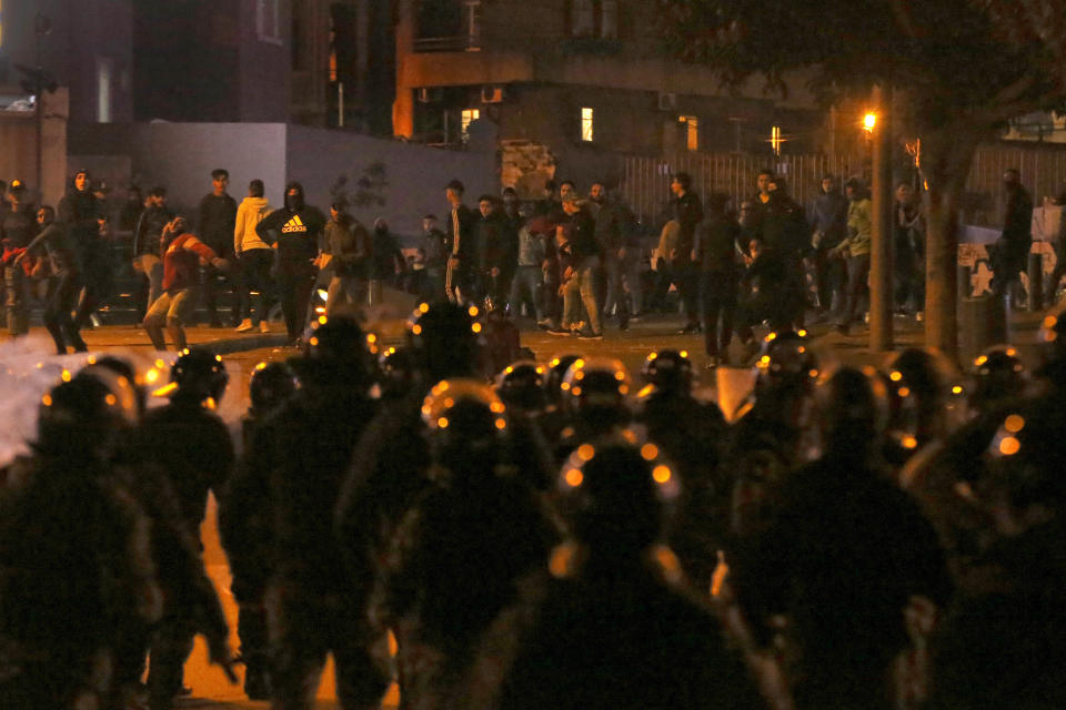 Supporters of the Shiite Hezbollah and Amal Movement groups, who are trying to attack the anti-government protesters, throw stones against the riot policemen, in Beirut, Lebanon, Wednesday, Dec. 11, 2019. Protesters are demanding a government made up of technocrats that would immediately get to work on the necessary reforms to address the economy. (AP Photo/Bilal Hussein)