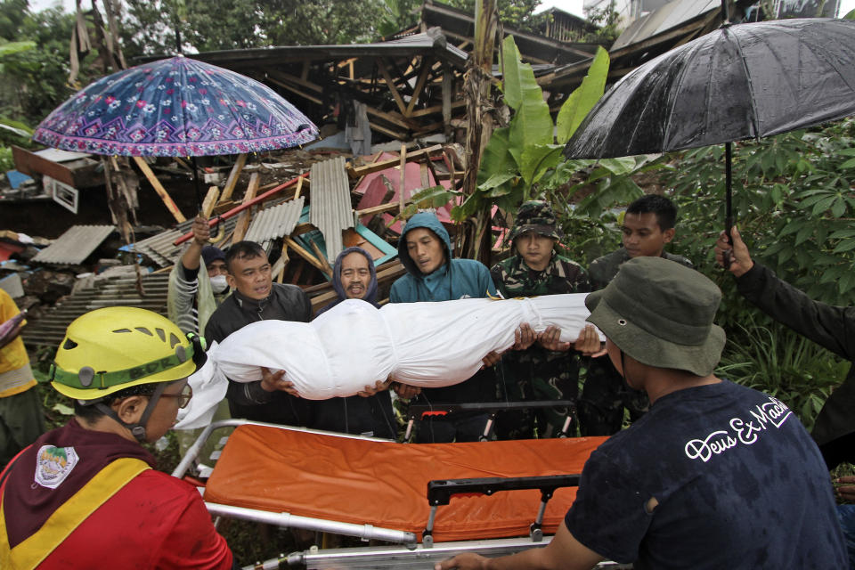 Rescuers and family members put the body of an earthquake victim onto a gurney before a burial in Cianjur, West Java, Indonesia, Wednesday, Nov. 23, 2022. More rescuers and volunteers were deployed Wednesday in devastated areas on Indonesia's main island of Java to search for the dead and missing from an earthquake that killed hundreds of people. (AP Photo)