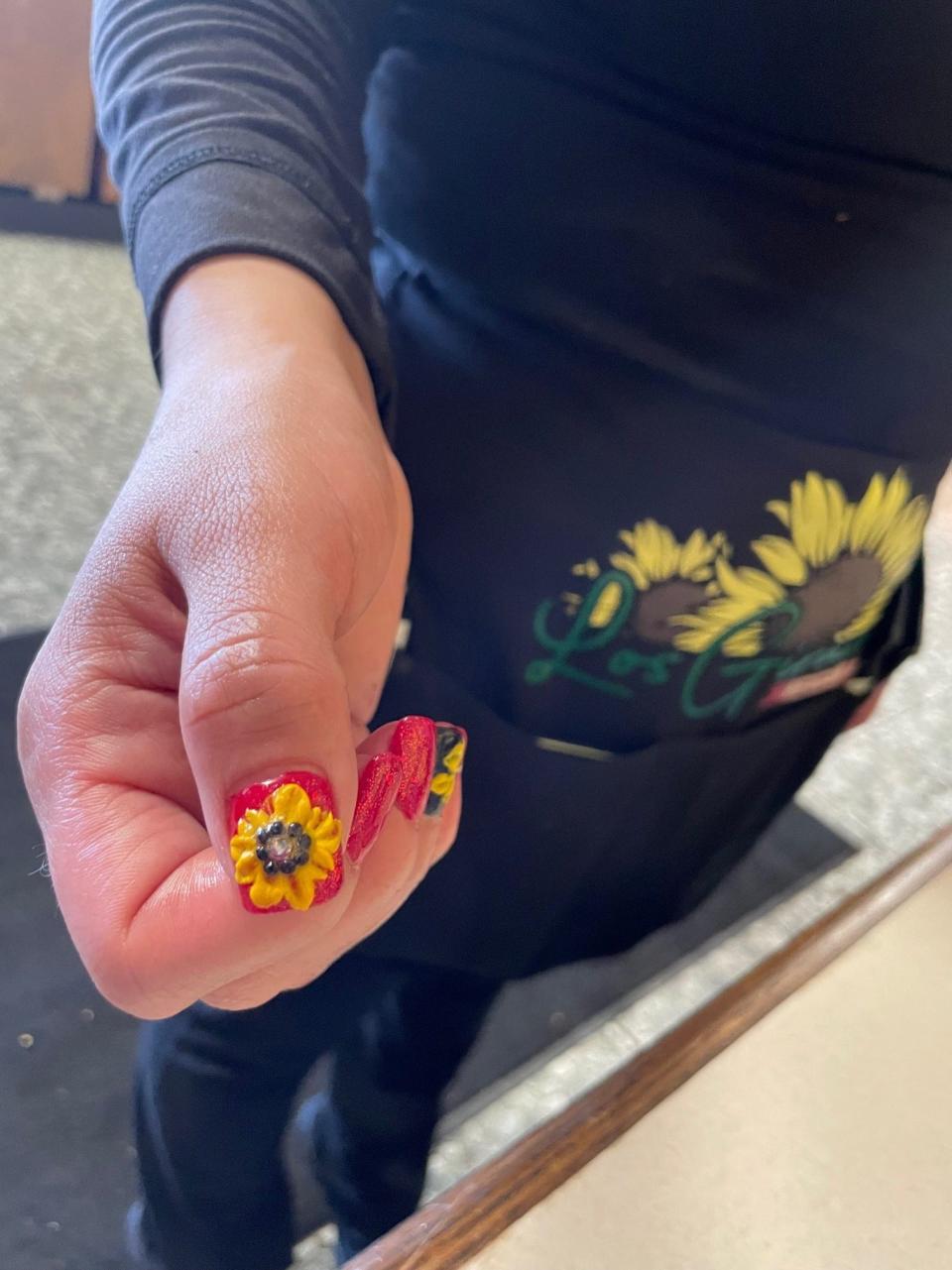 A server at Los Girasoles restaurant shows off her manicure, Feb. 27, 2022.