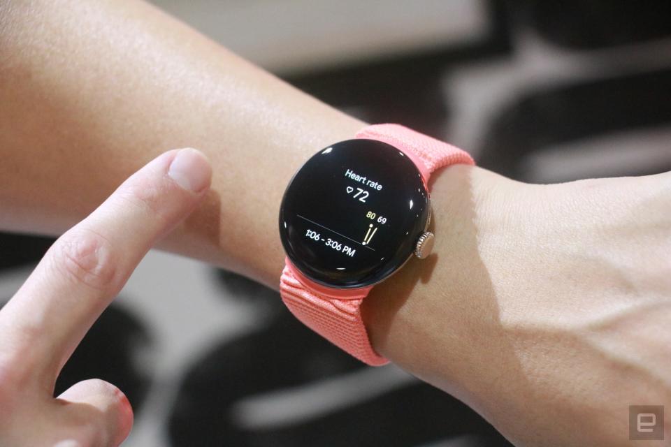 The Pixel Watch 2 with a peach woven band on a wrist, showing a heart rate reading.