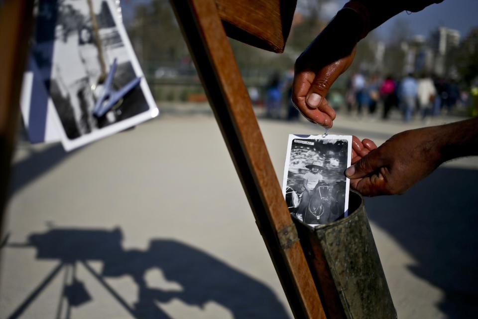 En esta imagen del 4 de septiembre de 2016, el fotógrafo Luis Maldonado seca un retrato recién revelado tomado con su vieja cámara de cajón durante una feria que celebra el Día de Independencia de Chile en Santiago de Chile. “Mientras yo he tomado una foto, ellos (mis colegas) han tomado más de 10”, se lamentó Maldonado sobre otros fotógrafos que hacen fotos digitales en la Plaza de Armas de Santiago de Chile. (AP Foto/Esteban Félix)