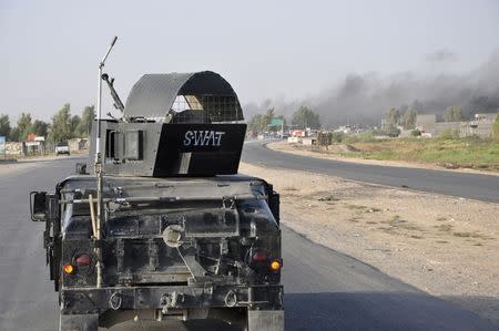 A convoy of the Iraqi security forces is pictured on the road during a patrol, as smoke rises from clashes with Islamic State fighters, in Diyala province July 18, 2014. REUTERS/Stringer