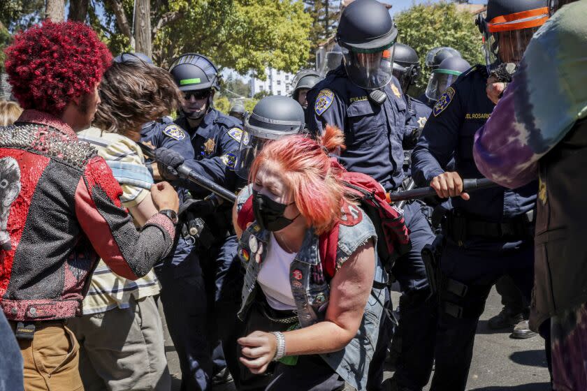 A protester winces in pain as police attempt to prevent the crowd from entering People's Park in Berkeley, Calif. on Wednesday, Aug. 3, 2022. Protesters gathered to decry the clearing out of the park in preparation for the development of student housing. (Bronte Wittpenn/San Francisco Chronicle via AP)