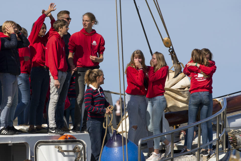 Teens wave, cry and hug as their schooner, carrying 25 Dutch teens who sailed home from the Caribbean across the Atlantic when coronavirus lockdowns prevented them flying, arrived at the port of Harlingen, northern Netherlands, Sunday, April 26, 2020. (AP Photo/Peter Dejong)