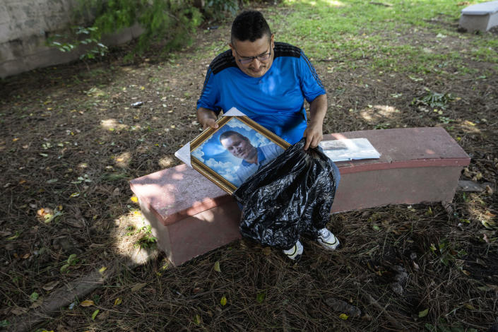 Jesus Joya places into a plastic bag a portrait of his younger brother Henry, who was taken from his home in April and detained under the ongoing "state of exception", in San Salvador, El Salvador, Wednesday, Oct. 12, 2022. A month after Henry’s arrest, guards at the Mariona prison north of San Salvador told Jesus that Henry was no longer there. That’s all they would say. In September Jesus learned that Henry had died in the Mariona prison on May 25, barely a month after his arrest. (AP Photo/Moises Castillo)