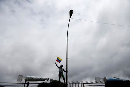 A demonstrator rises a Venezuelan flag in front of an Air Force base while rallying against Venezuelan President Nicolas Maduro's government in Caracas, Venezuela, June 24, 2017. REUTERS/Ivan Alvarado