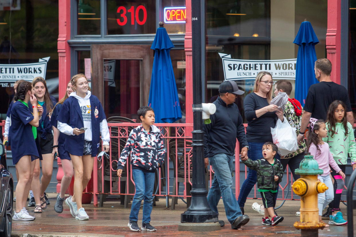 Groups of people walk in the Court Ave. district of Des Moines, Iowa, after Gov. Kim Reynolds signed a bill into law that bans future mask mandates for schools, cities and counties, May 20, 2021.  REUTERS/Rachel Mummey