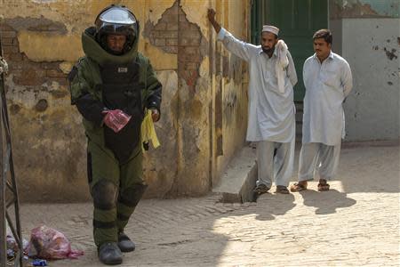 A technician from Pakistan's top bomb disposal unit uses plastic bags as gloves during a bomb search operation in Peshawar October 2, 2013. REUTERS/Zohra Bensemra