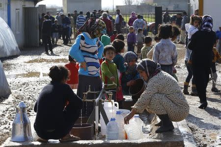 Kurdish refugees from the Syrian town of Kobani wait to fill their jerrycans around a clean water source at a refugee camp in the border town of Suruc, Sanliurfa province February 1, 2015. REUTERS/Umit Bektas