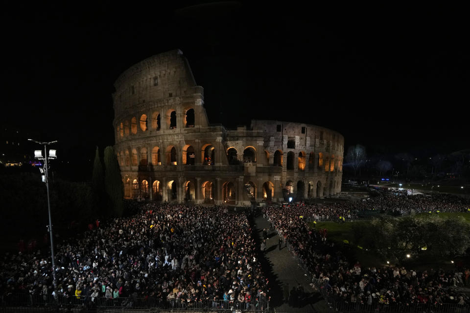 People stand in front of the Colosseum during a Via Crucis (Way of the Cross) torchlight procession on Good Friday, in Rome, Friday, March 29, 2024. (AP Photo/Andrew Medichini)