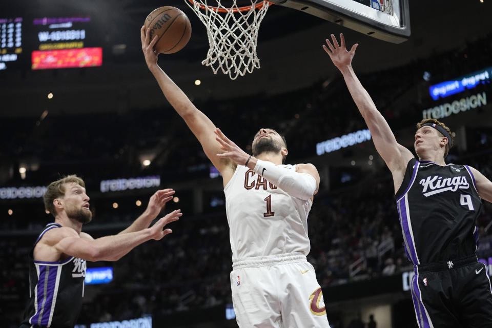 Cleveland Cavaliers guard Max Strus (1) shoots between Sacramento Kings forward Domantas Sabonis, left, and guard Kevin Huerter (9) in the second half of an NBA basketball game, Monday, Feb. 5, 2024, in Cleveland. (AP Photo/Sue Ogrocki)