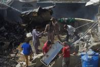 Rescue workers gather at the site after a Pakistan International Airlines flight crashed in a residential neighbourhood in Karachi on May 22, 2020. - A Pakistan passenger plane with more than 100 people believed to be on board crashed in the southern city of Karachi on May 22, the country's aviation authority said. (Photo by Asif HASSAN / AFP) (Photo by ASIF HASSAN/AFP via Getty Images)