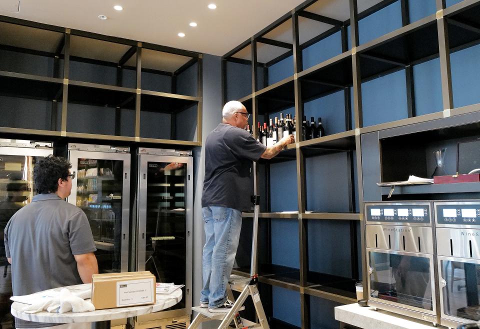 Bottles of wine are being stocked on shelves at Toscana an Italian steakhouse in the Red Cedar Development Tuesday, Aug. 22, 2023. The restaurant will open on Aug. 31.