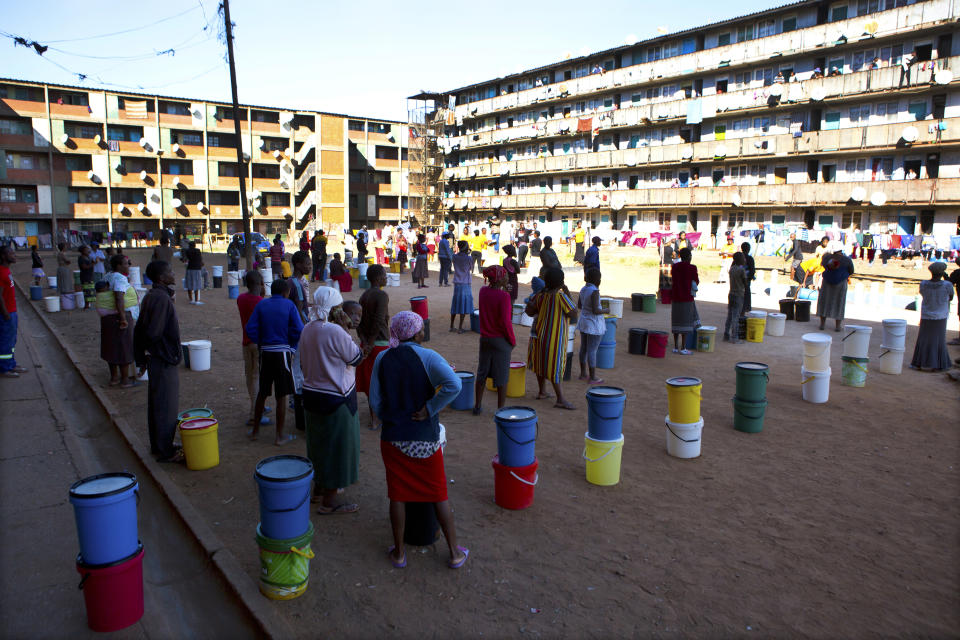 In this April, 24, 2020, photo, people wait to fetch water from a row of communal taps that the group Doctors Without Borders provided in a suburb of Harare, Zimbabwe. For people around the world who are affected by war and poverty, the simple act of washing hands is a luxury, even during the coronavirus pandemic. In Zimbabwe, clean water is often saved for daily tasks like doing dishes and flushing toilets. (AP Photo/Tsvangirayi Mukwazhi)