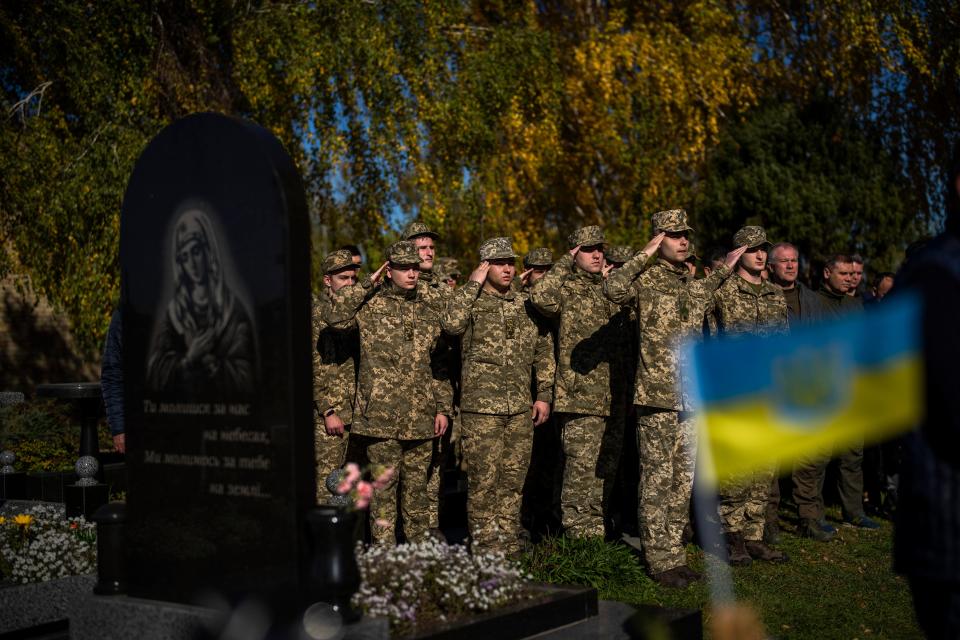 Soldiers salute as the Ukrainian national anthem is played at the funeral of Colonel Oleksiy Telizhenko in Bucha, near in Kyiv on Oct. 18, 2022.