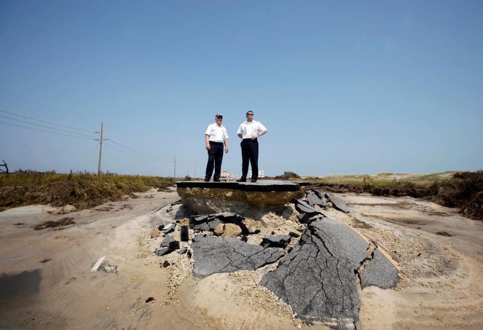 NCDOT helicopter pilots Ray Edwards, left, and Terry Carlyle stand on the edge of a washed out N.C. 12 about 8-miles south of the Bonner Bridge in the Pea Island National Wildlife Refuge on Monday, August 29, 2011. They had flown four DOT officials down to survey the numerous breaches caused by Hurricane Irene.