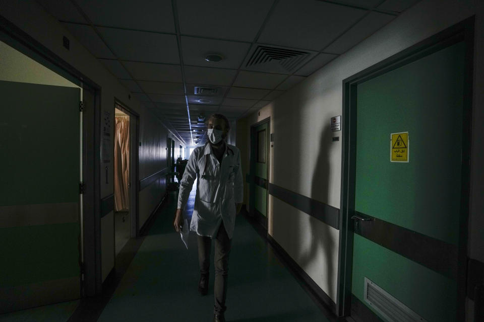 A doctor walks through a corridor of the government-run Rafik Hariri University Hospital during a power outage in Beirut, Lebanon, Wednesday, Aug. 11, 2021. Many private hospitals, who offer 80% of Lebanon's medical services, are shutting down because of lack of resources or turning away patients who can't pay. (AP Photo/Hassan Ammar)