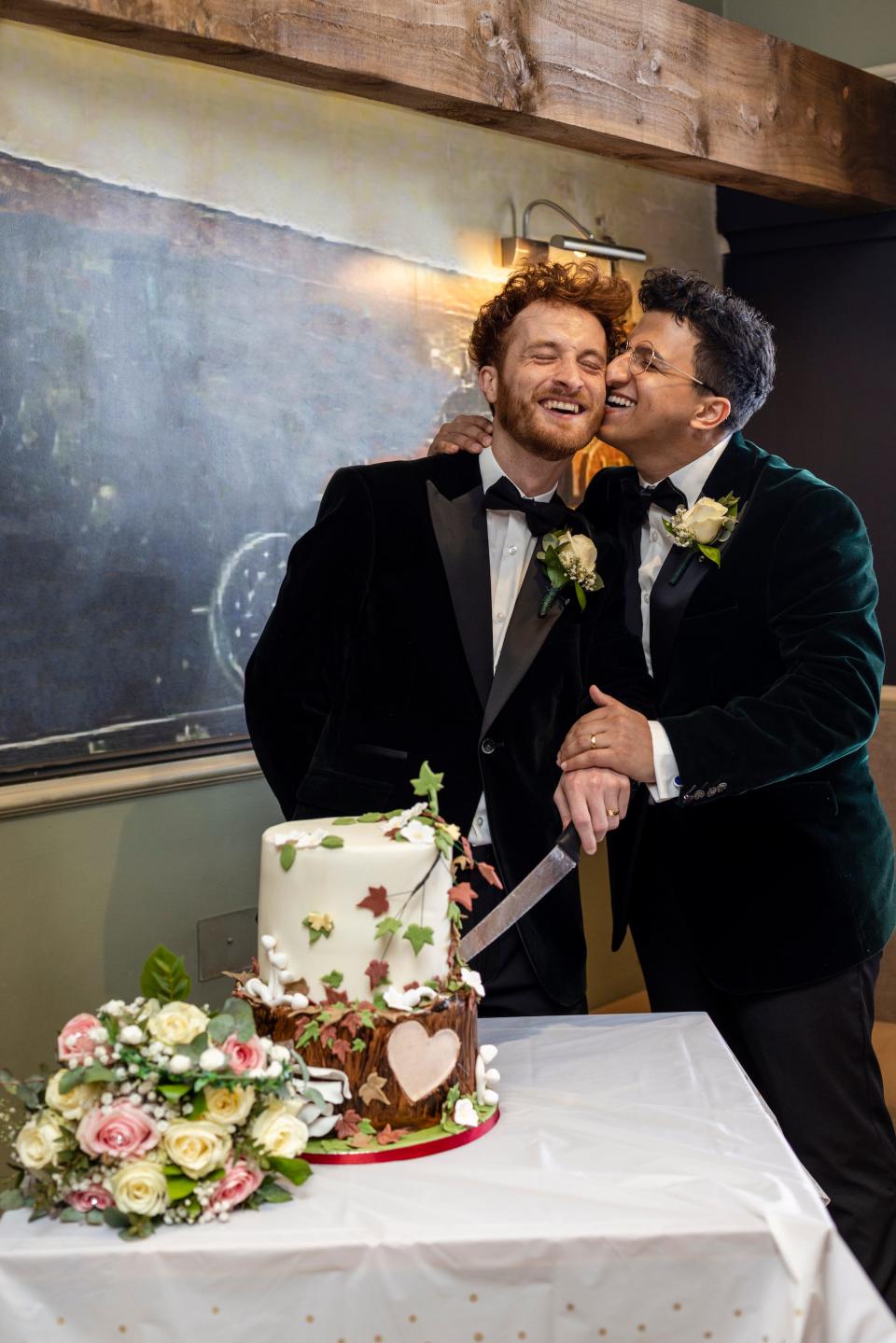 A couple cuts their wedding cake and lean together.