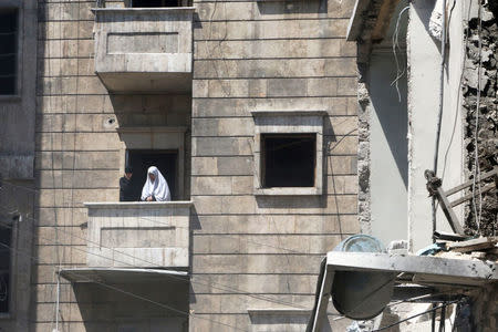 Women stand on a balcony as they react after airstrikes in the rebel held area of al-Kalaseh neighborhood of Aleppo. REUTERS/Abdalrhman Ismail