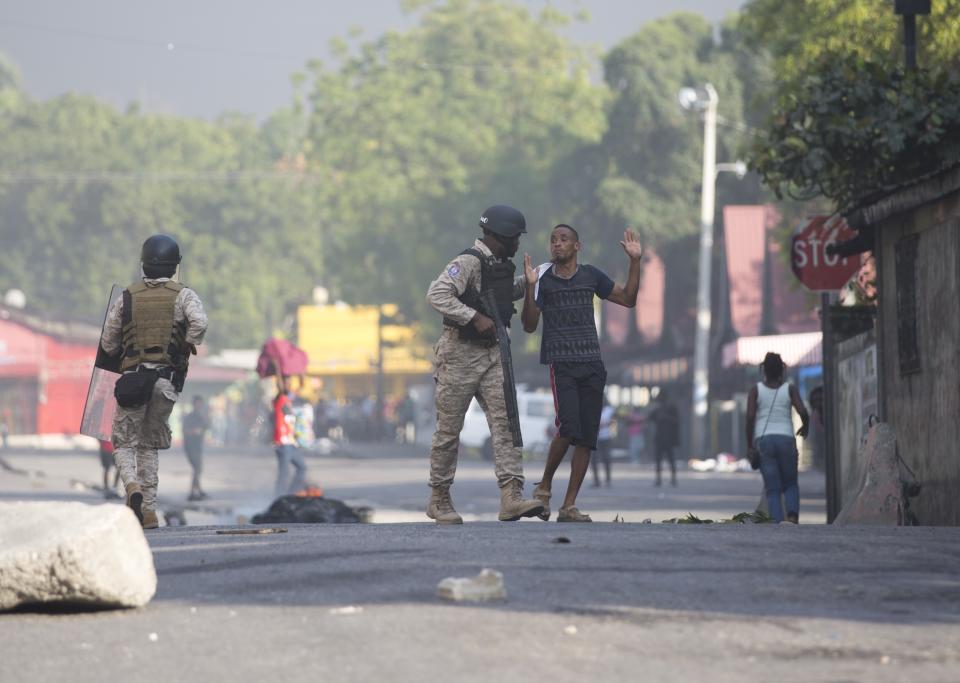 A protester is detained by a police officer during a protest to demand the resignation of President Jovenel Moise and demanding to know how Petro Caribe funds have been used by the current and past administrations, in Port-au-Prince, Haiti, Saturday, Feb. 9, 2019. The man was later released. Much of the financial support to help Haiti rebuild after the 2010 earthquake comes from Venezuela's Petro Caribe fund, a 2005 pact that gives suppliers below-market financing for oil and is under the control of the central government. (AP Photo/Dieu Nalio Chery)